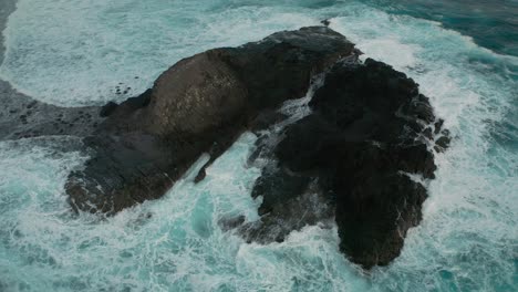 Wellen,-Die-Auf-Isolierten,-Von-Wasser-Umgebenen-Felsen-Krachen,-Antenne