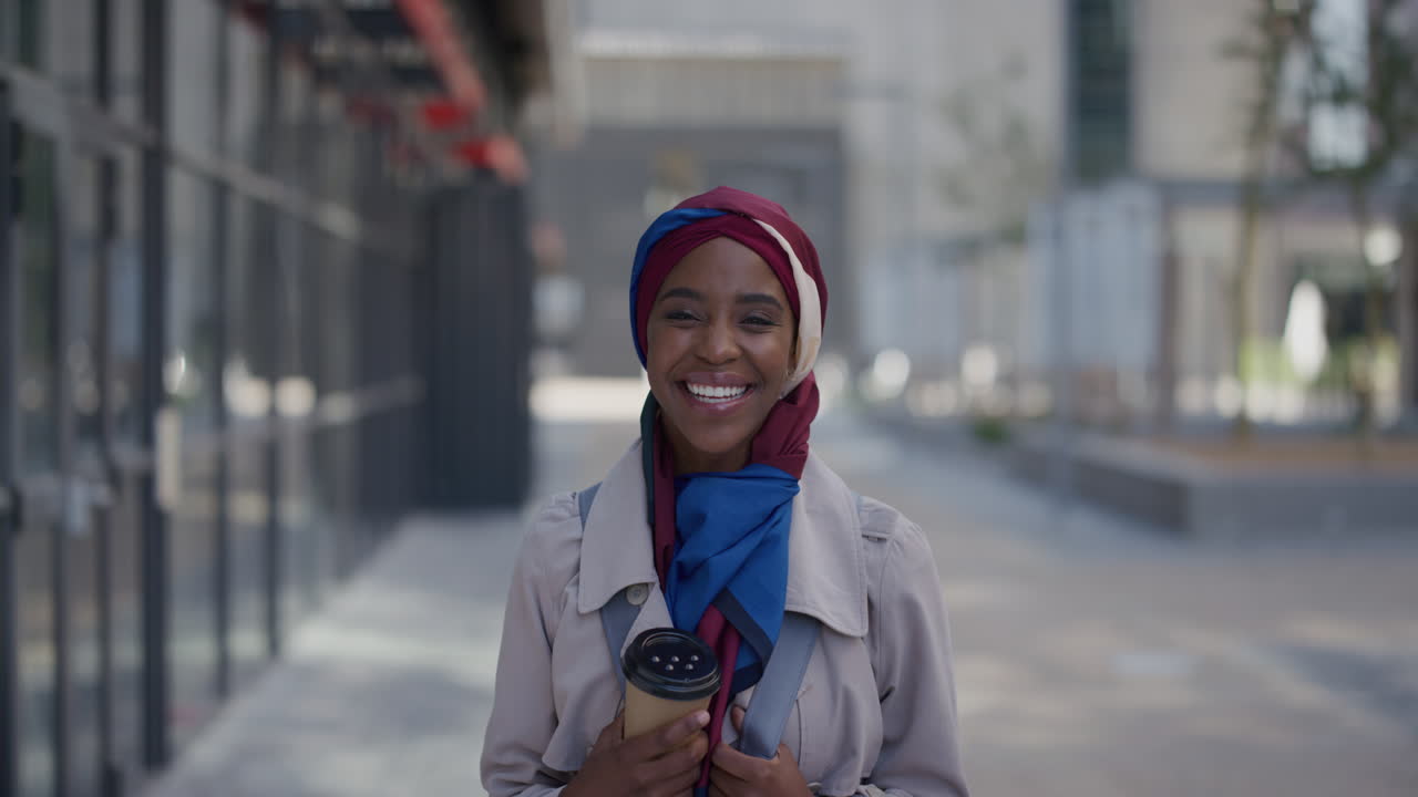 ritratto giovane felice donna afroamericana che ride godendo di uno stile di vita felice in città bella donna d'affari musulmana nera che sembra allegra indossando un hijab e un foulard in slow motion