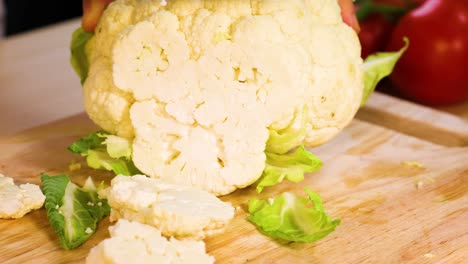 slicing cauliflower with a knife on a board