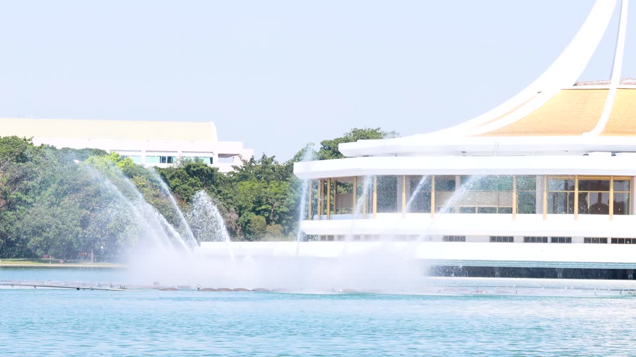 A serene fountain show in Suan Luang Rama IX Park, Bangkok, with clear skies and calm waters captured in bright daylight
