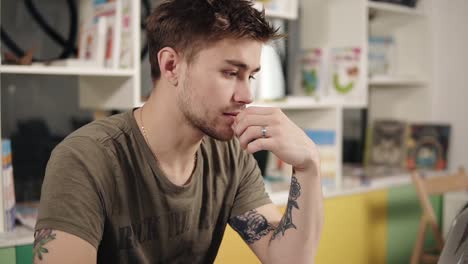 un programador atractivo y sexy con tatuajes en los brazos pensando mucho en algo.