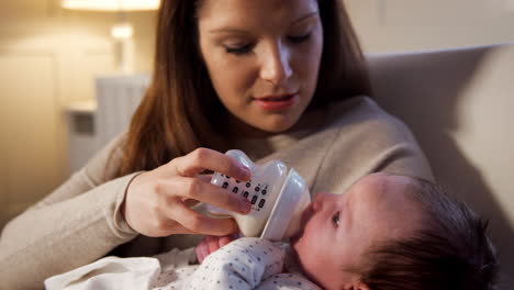 mother in nursery feeding newborn baby from bottle