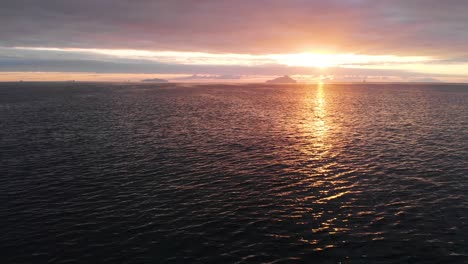 Ein-Ruhiger-Ozean-Mit-Inseln-Und-Einem-Wolkigen-Sonnenaufgang,-Der-Sich-Im-Wasser-Spiegelt