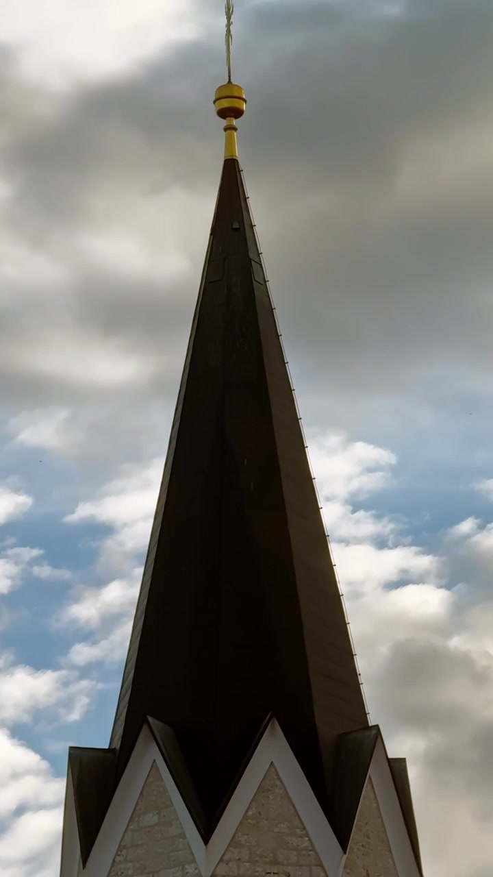 Campanário de igreja subindo em um céu nublado dramático na histórica Kranj, Eslovênia, vista vertical ascendente