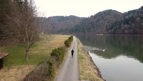 in an autumnal landscape with colorfully spotted trees, a young man is visible running along a path