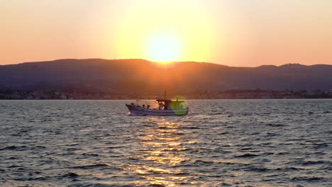 4k 24fps handheld backlit shot of fishing boat cruising in front of the sun at dawn