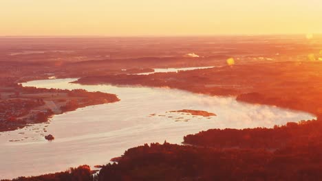 sunrise glows across misty daugava river seen from helicopter in soft light