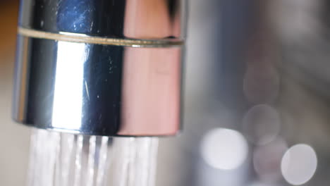 macro close up of a kitchen faucet turning on and water flowing out