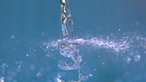 a small hand mixer or electric stick blender spinning near a stream of water and when put against it it splatters the water and makes it splash in slow motion