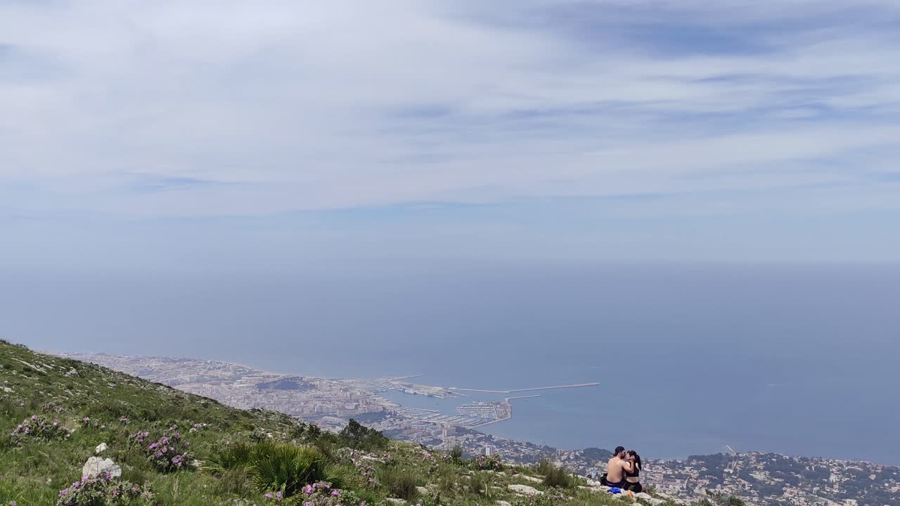 Couple Enjoying Panoramic View of Coastal City and Ocean from a Mountain