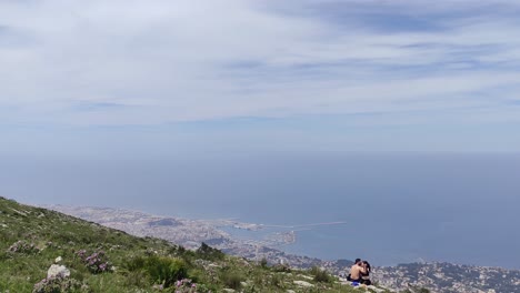couple enjoying panoramic view of coastal city and ocean from a mountain