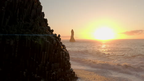 aerial shot past hexagonal columns reynisfjara towards sea stacks iceland