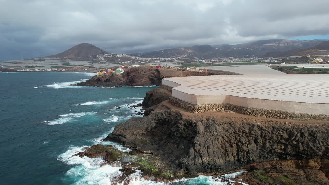 maravillosa toma aerea en el lugar conocido como punta de galdar y al fondo la montaña de galdar y las casas construidas en la costa