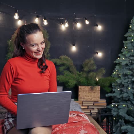 happy lady is typing congratulations with winter holidays on laptop. happy woman in good mood before christmas