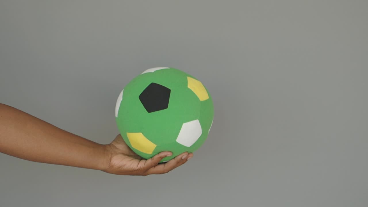 Hand holding a green soccer ball