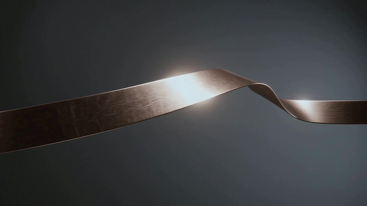 Twisting bronze ribbon undulating, looping in studio set, catching spotlight to showcase finish