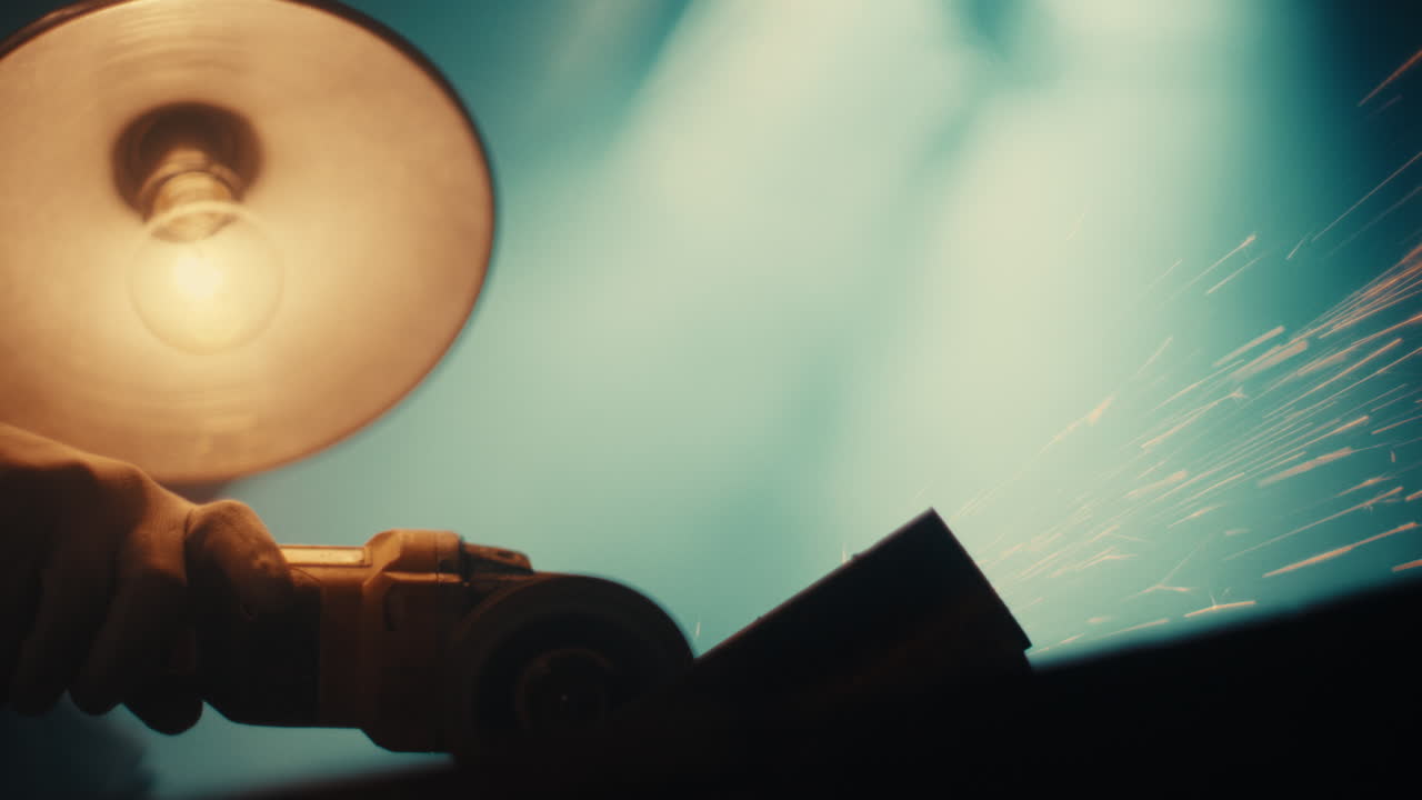 Angle grinder cutting steel with workshop lamp glowing swings above
