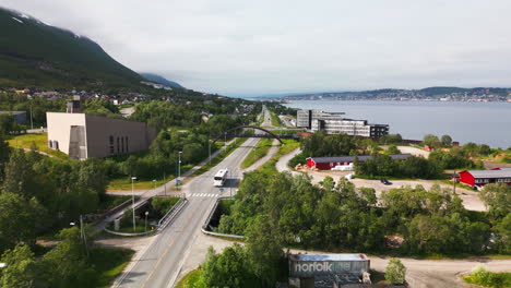 white bus on tromsoysundvegen next to fjord in tromso, norway