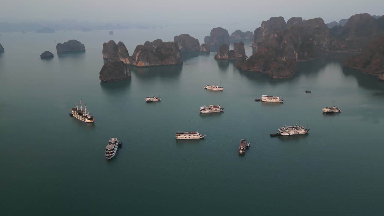 Aerial 4K drone footage over Ha Long Bay, Vietnam, showing tourist boats navigating among limestone karsts and emerald waters