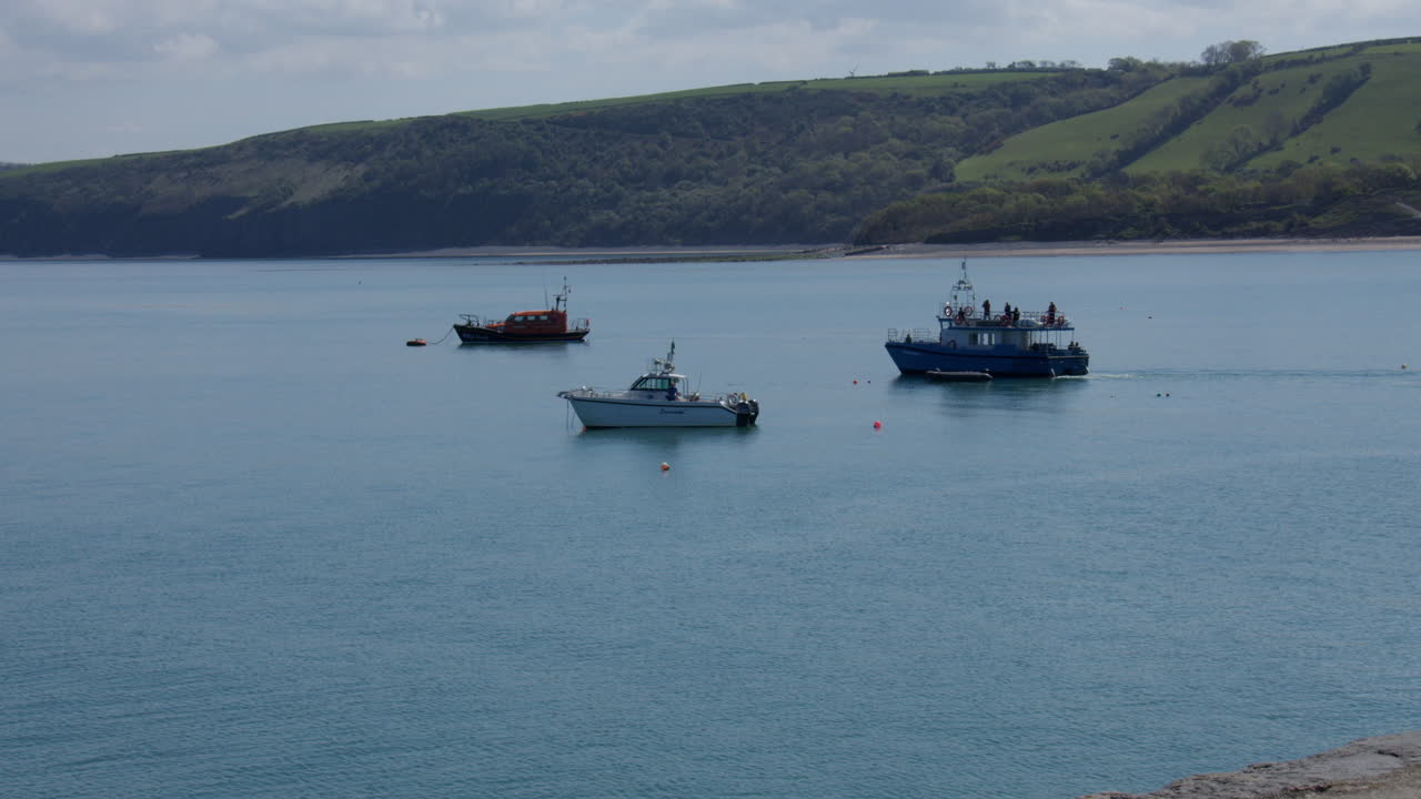 Wide shot of tourist boats leaving new quay harbour with lifeboat in background