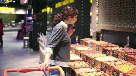 Young-girl-trying-to-choose-nuts-in-a-supermarket.-Buyer-asking-for-help