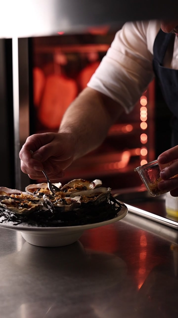 Chef che guarnisce con cura ostriche fresche in una cucina professionale