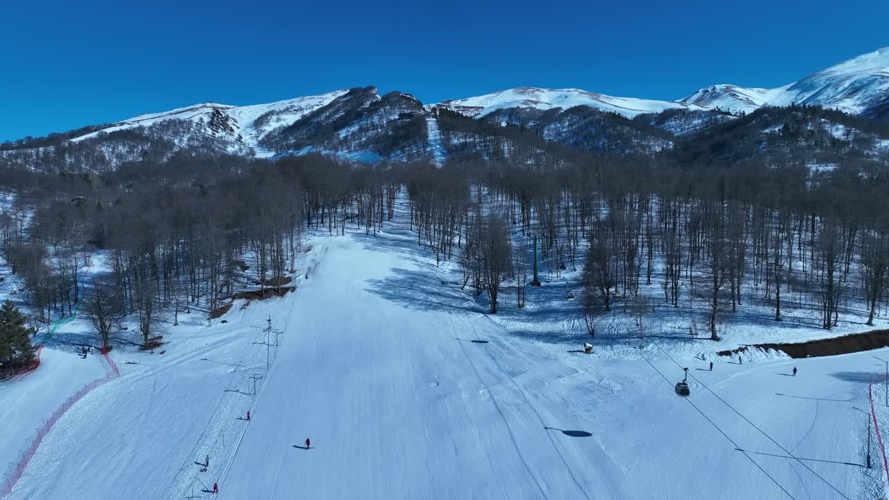 An aerial view of a winter sports complex with ski lifts, slopes, and facilities, capturing the vibrant energy and excitement of a snowy day at the resort