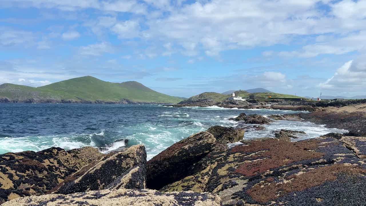 Ireland Epic Locations rocky shoreline crashing waves and lighthouse with mountains Valencia Island kerry Ireland