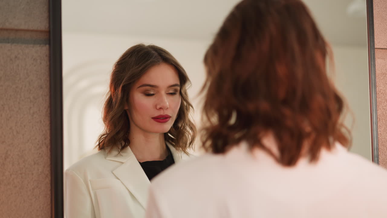 Giovane donna che si guarda allo specchio esaminando il trucco professionale