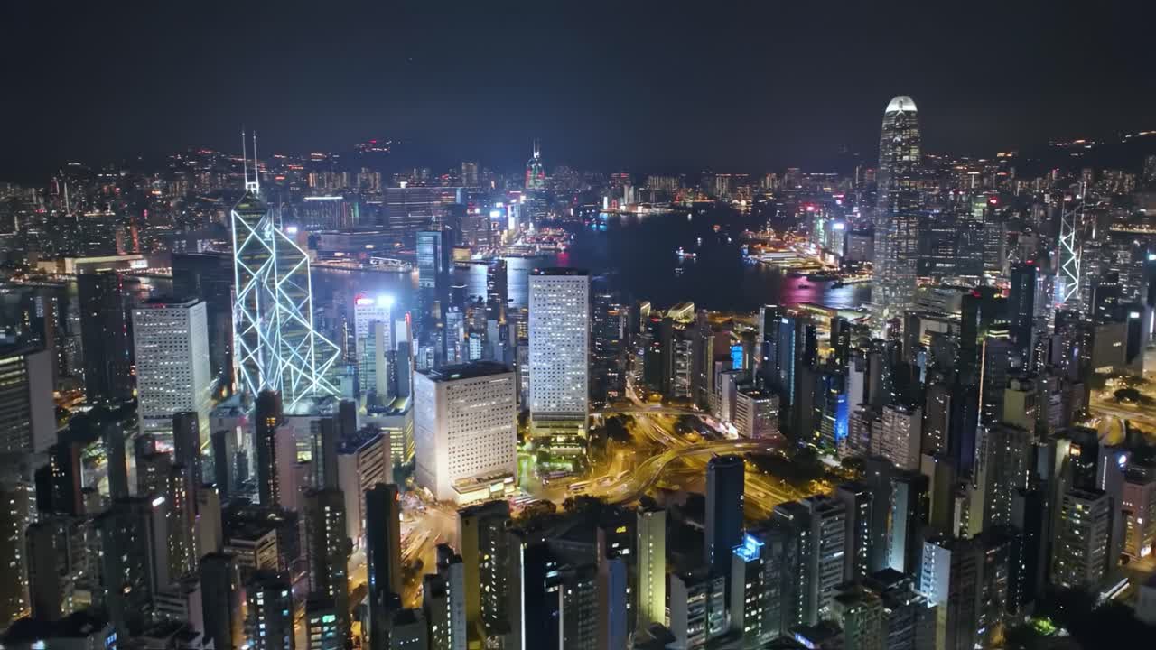 Explore a dynamic city skyline at night, filled with bright lights reflecting off skyscrapers and the harbor. The bustling urban landscape showcases modern architecture and vibrant energy.
