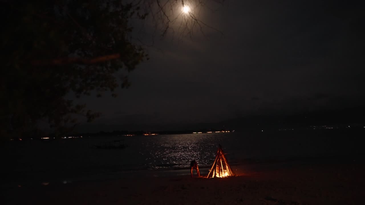 fogueira na praia sob a lua cheia refletida no mar, destino de viagem tropical komodo na indonésia