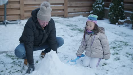 grandfather and granddaughter having fun in the snow