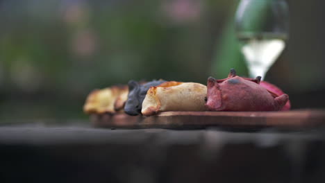 Imagen-En-Cámara-Lenta-De-Una-Tabla-De-Empanadas-Con-Una-Copa-De-Vino-Torrontés-De-Fondo