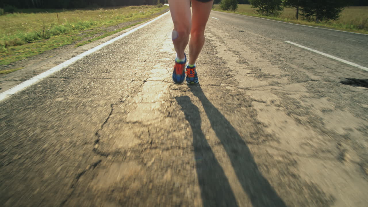 las piernas de una deportista corriendo por la carretera