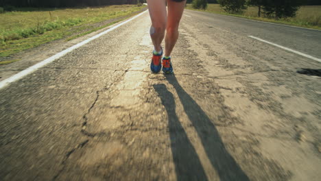 legs of sportswoman running on road