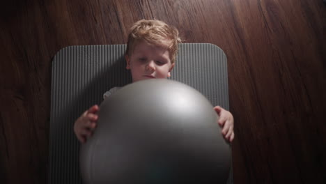 Cute-little-boy-holds-silver-gymnastic-ball-in-hands