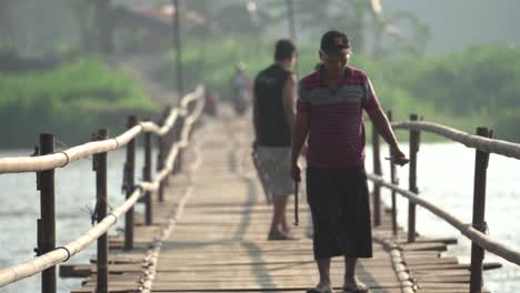 a group of people are maintaining and repairing a bridge made of wood. the bridge connects the villages of bantul and kulonprogo.
