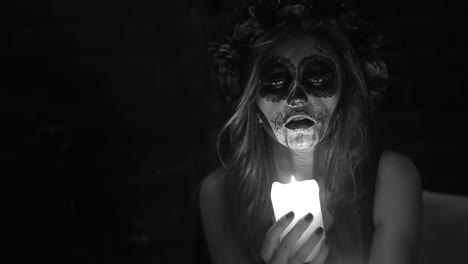 woman with sugar skull makeup holding a candle