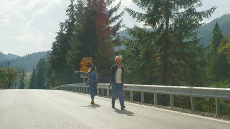 couple hikers stop car outside. mountain tourists move hands on forest highway.