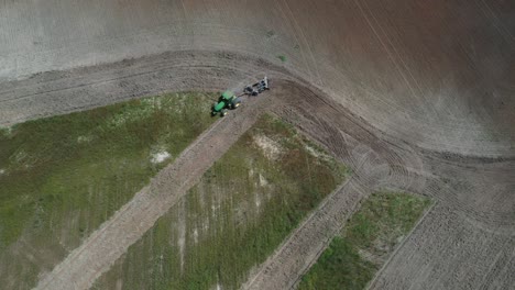 a tractor plowing a field to plant soybeans in the brazilian savannah - straight down aerial view