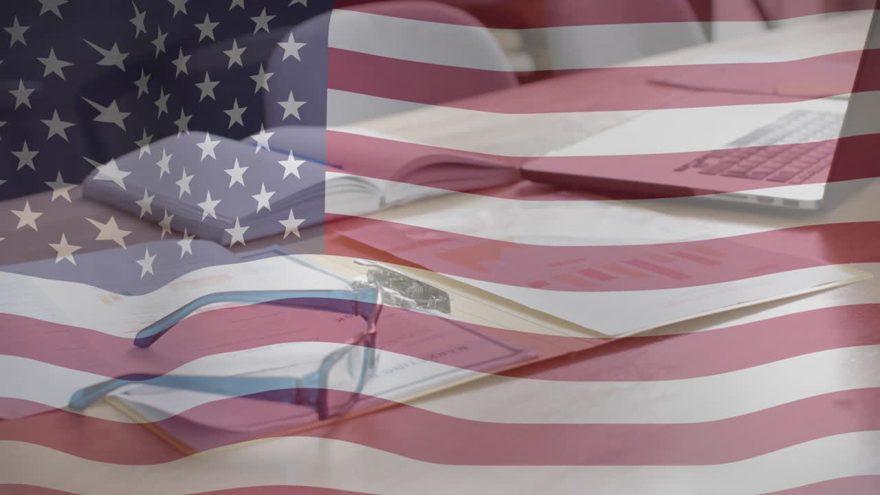 Animazione della bandiera americana su una scrivania d'ufficio con documenti, occhiali e un laptop.