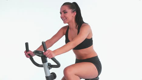 bruneta deportiva y alegre usando una bicicleta de ejercicio
