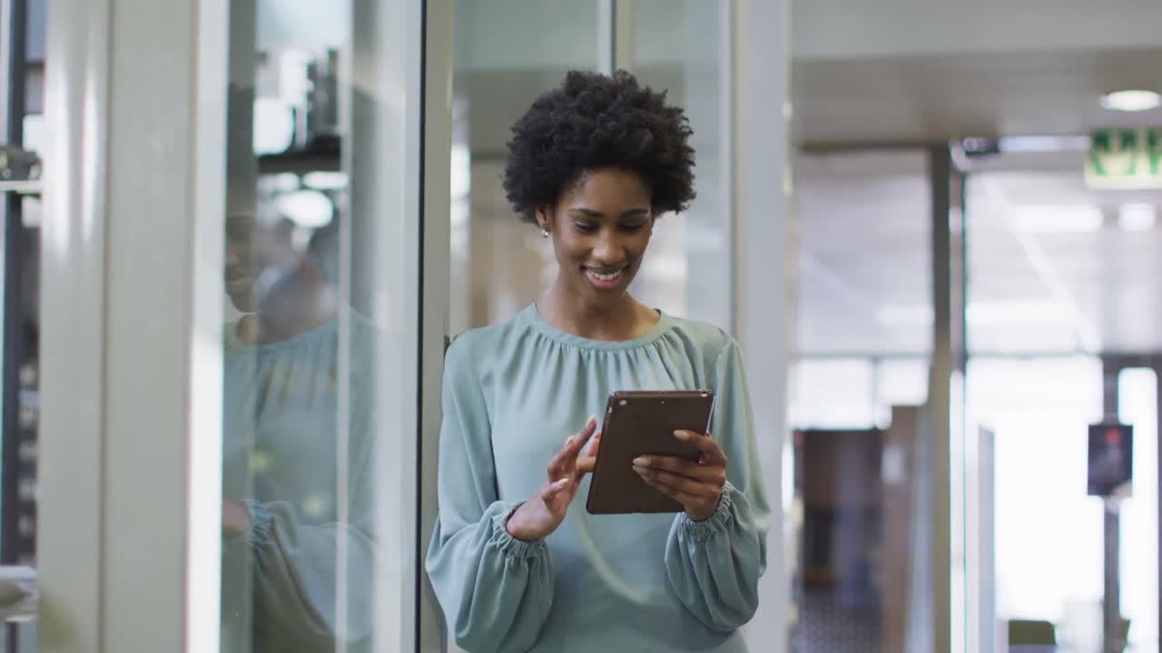 Video of happy african american businesswoman using tablet in office