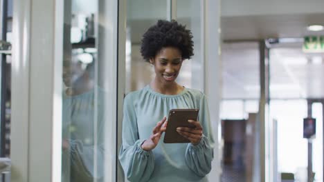 Video-of-happy-african-american-businesswoman-using-tablet-in-office