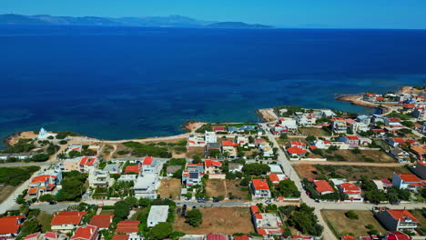 Pueblo-Griego,-Casas-Con-Techos-Anaranjados-Y-Océano-De-Fondo-(foto-Aérea-Con-Dron)