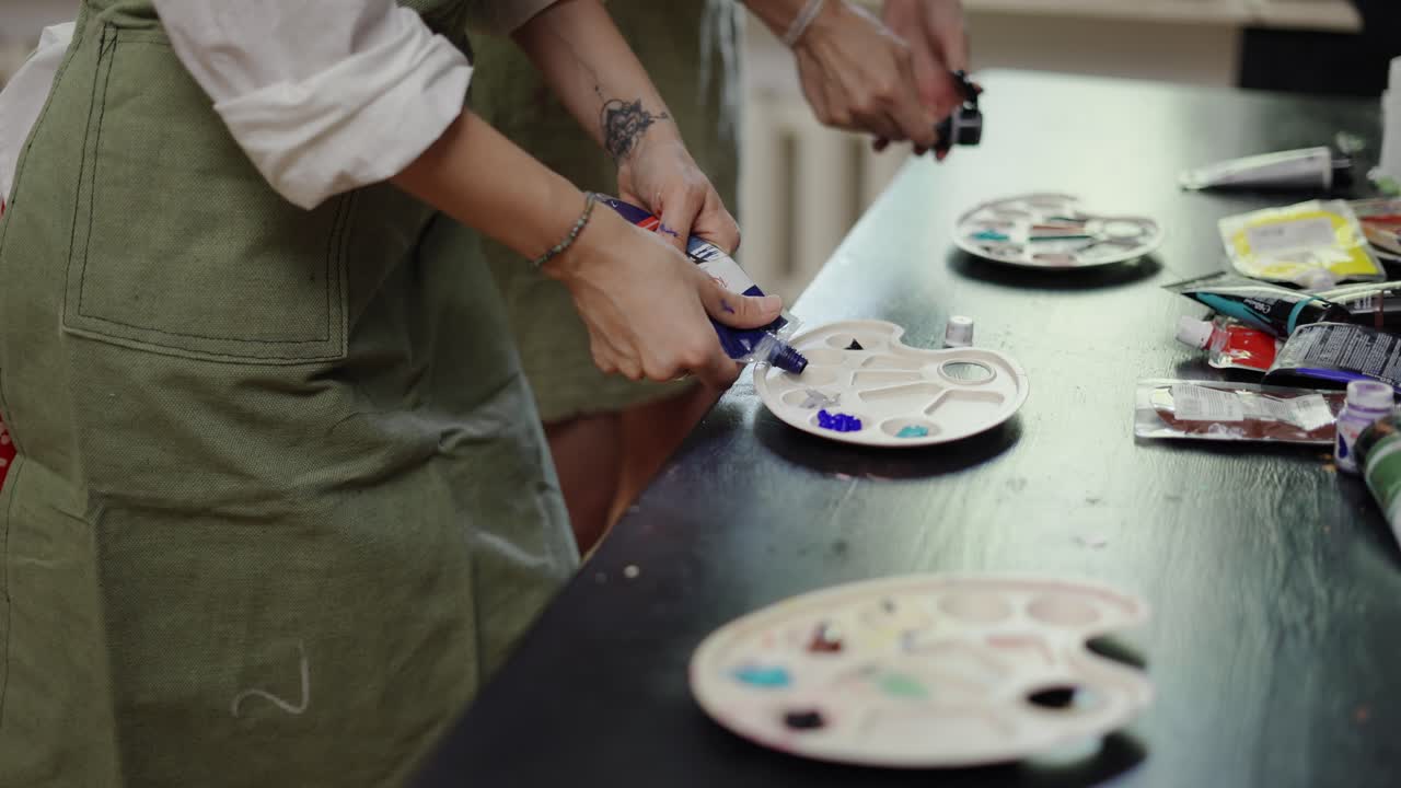 manos femeninas vierte pintura diversa en una paleta en el taller