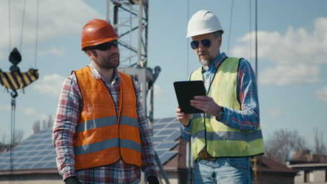 construction workers discussing project on rooftop with solar panels