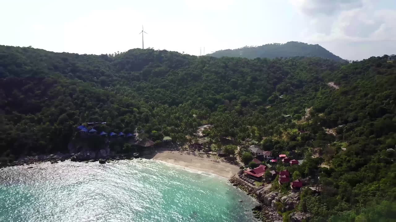 Aerial view at tropical island. Camera moves backwards and up from coastline into the sea. Bright sunny day. Koh Tao. Thailand