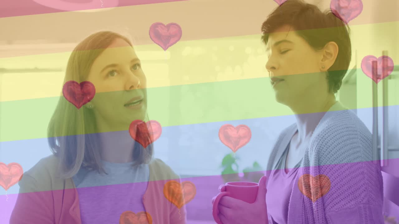 animación de emojis de corazón y bandera del arco iris sobre una pareja de mujeres caucásicas en casa