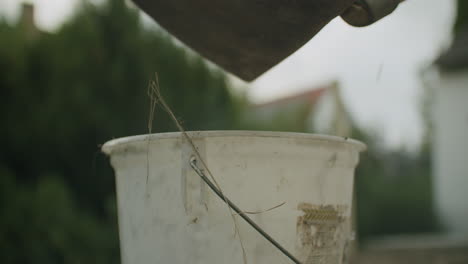 handheld shot of a female shoveling dirt into a white bucket